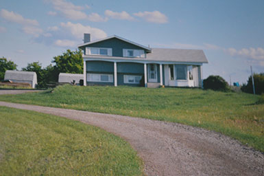 Photo of house viewed across field and curved drive
